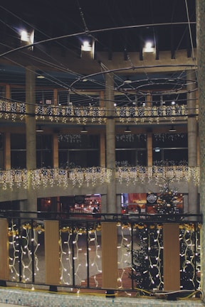 A festive event space decorated with warm lights and guests enjoying drinks.