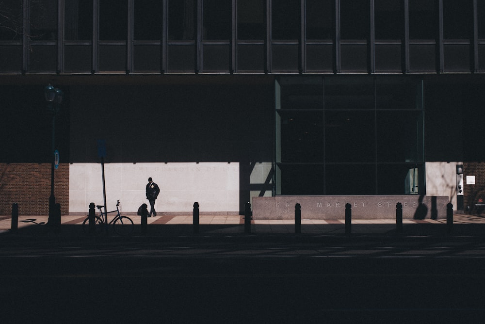 man walking near bicycle beside building