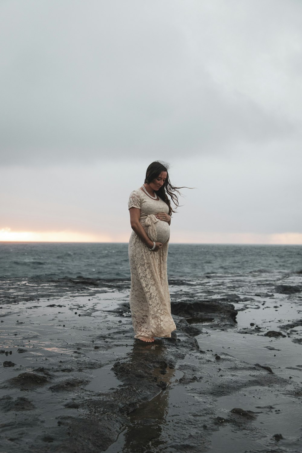 woman standing rock under gray sky