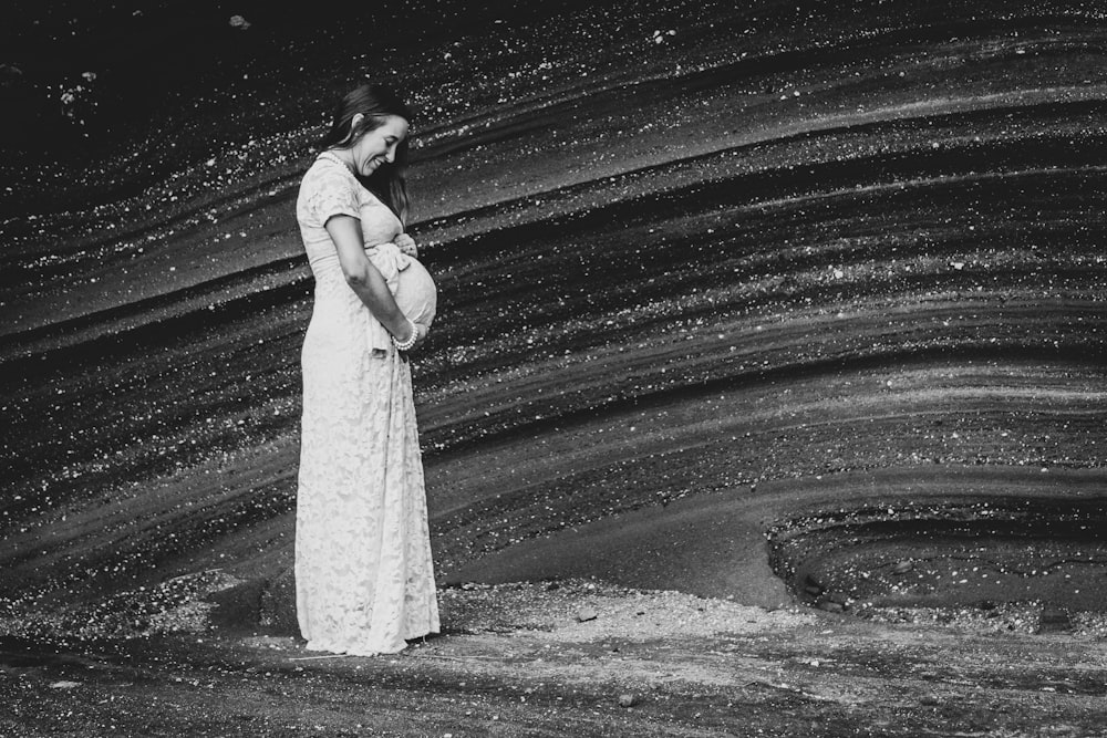 pregnant woman in white dress holding her tummy