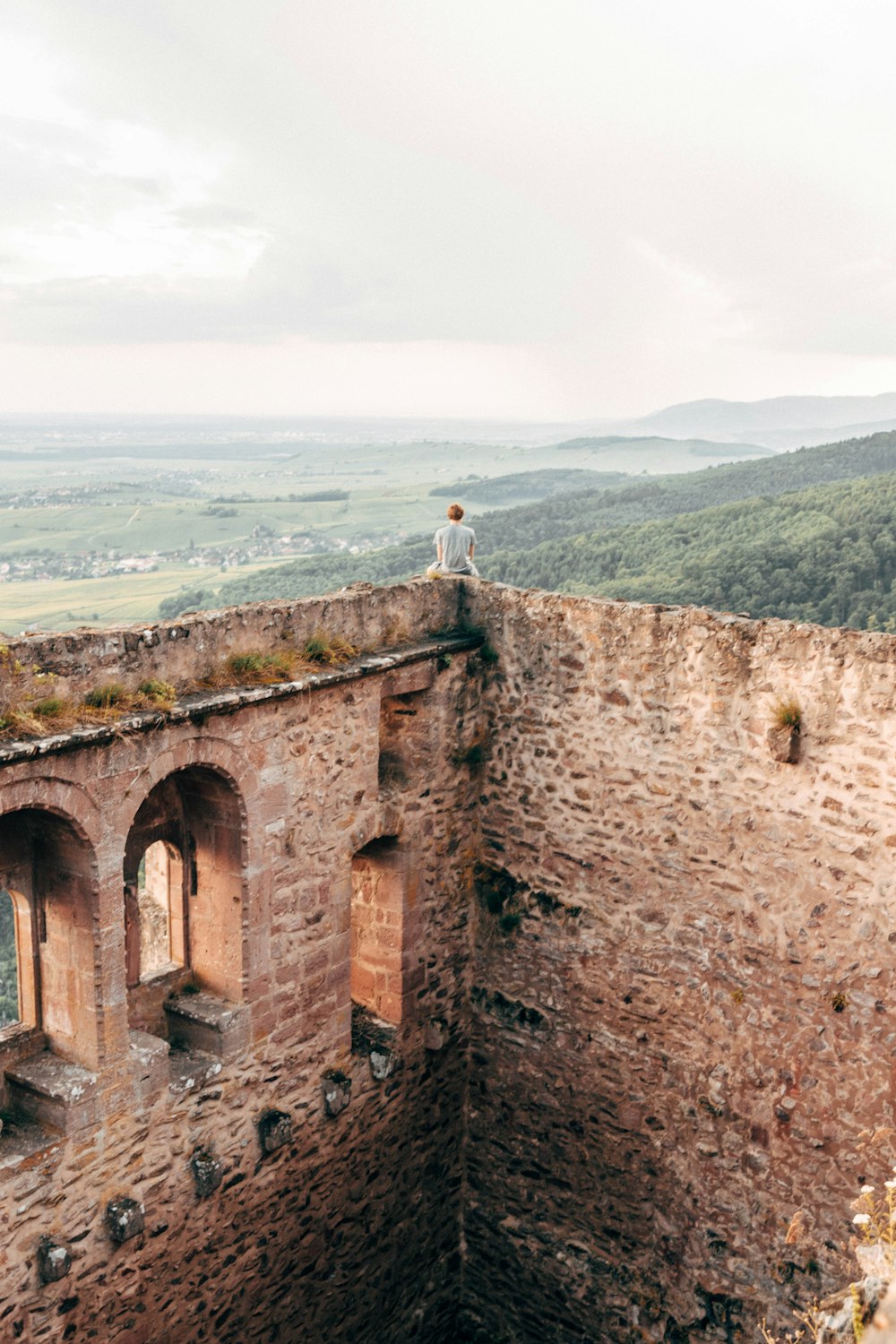 person sitting on top of building over looking mountains