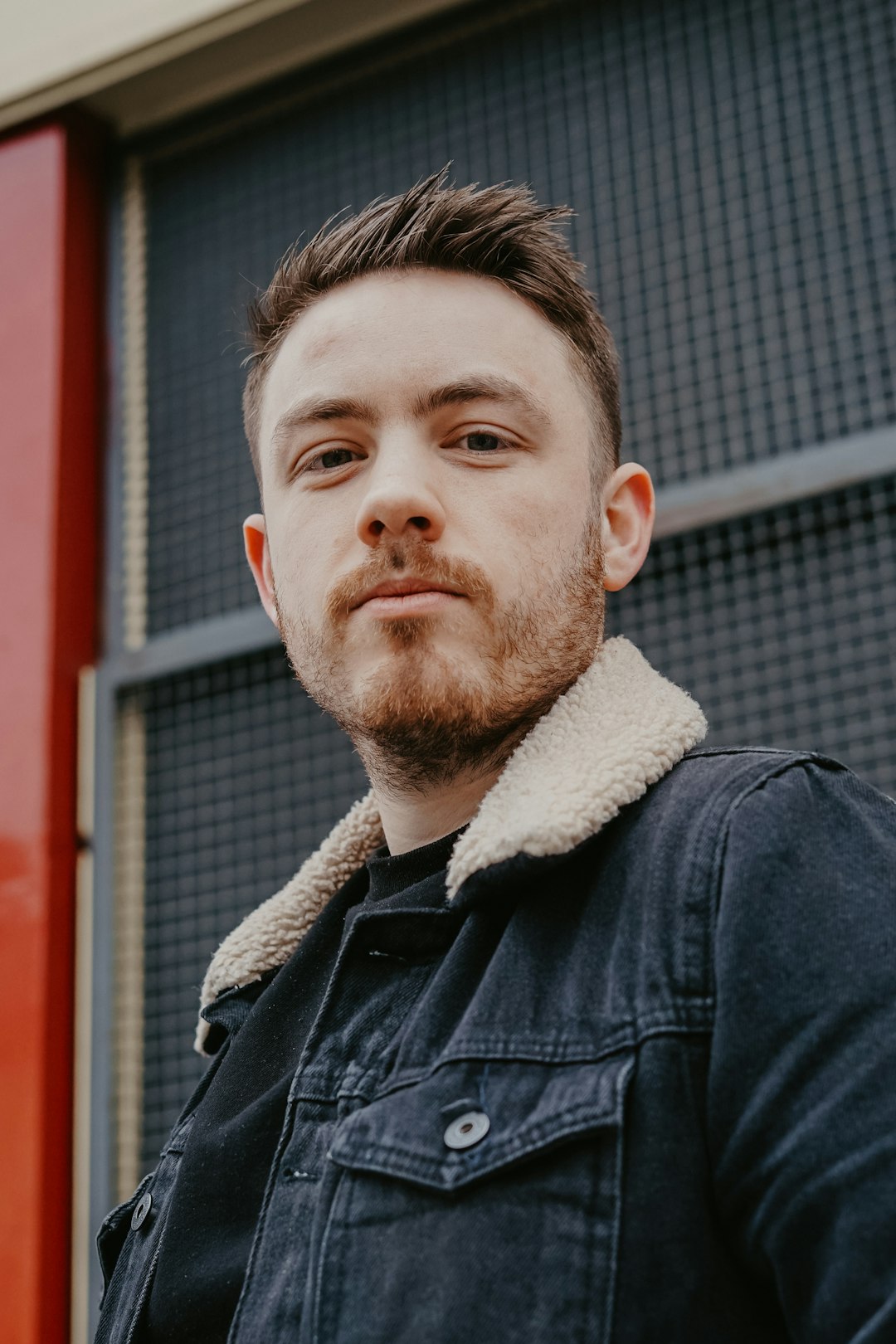 man wearing black denim jacket near building