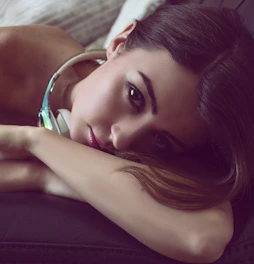 Softly lit room with a person peacefully reclining, wearing sleek headphones.