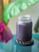 Refreshing red berry smoothie in a mason jar with scattered fresh berries around.