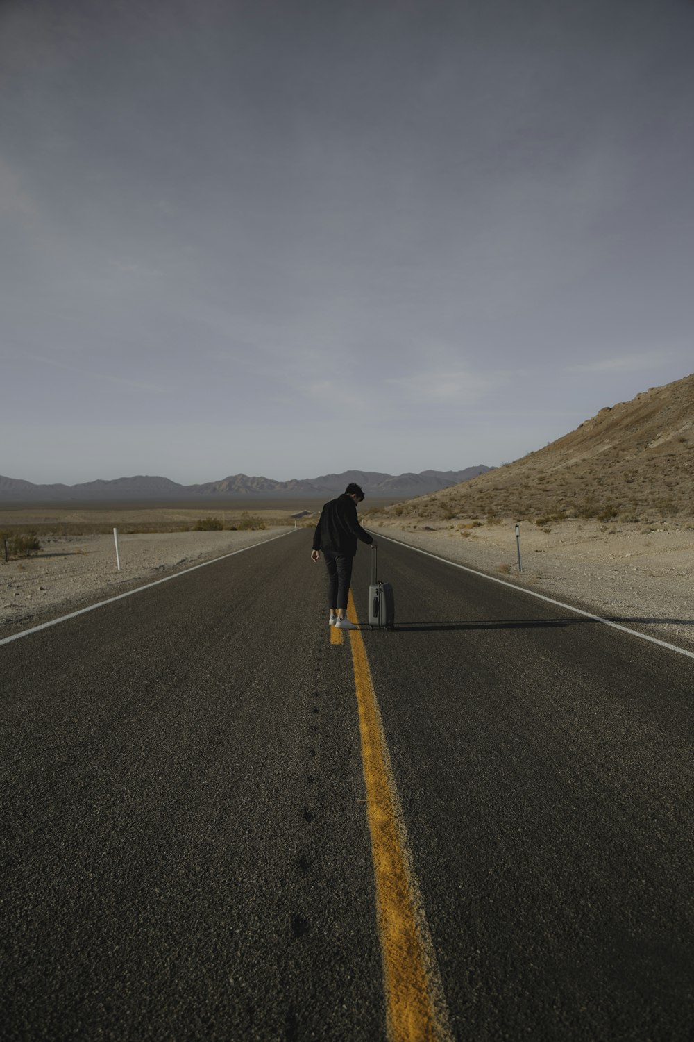 person holding luggage on road during daytime