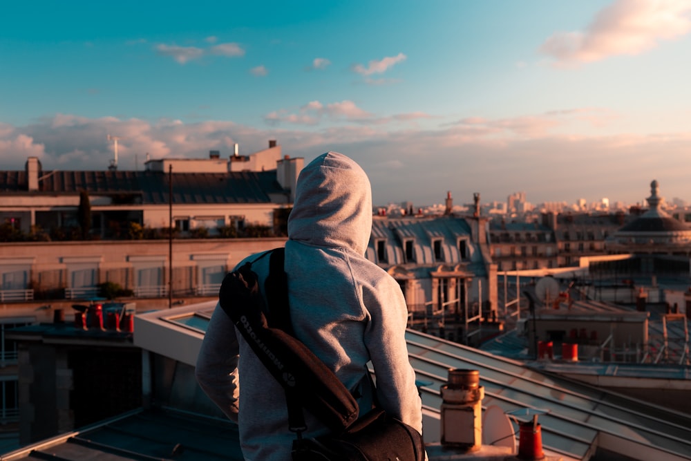 person wearing gray pullover hoodie standing on building