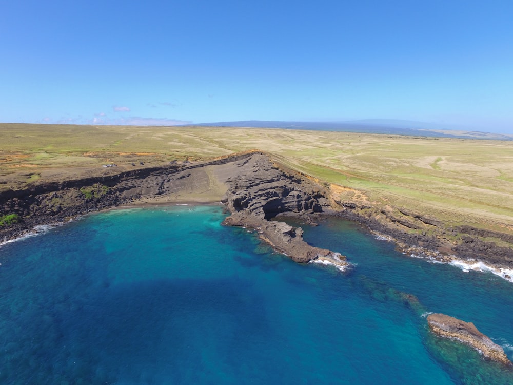 high-angle photography of blue sea beside green land