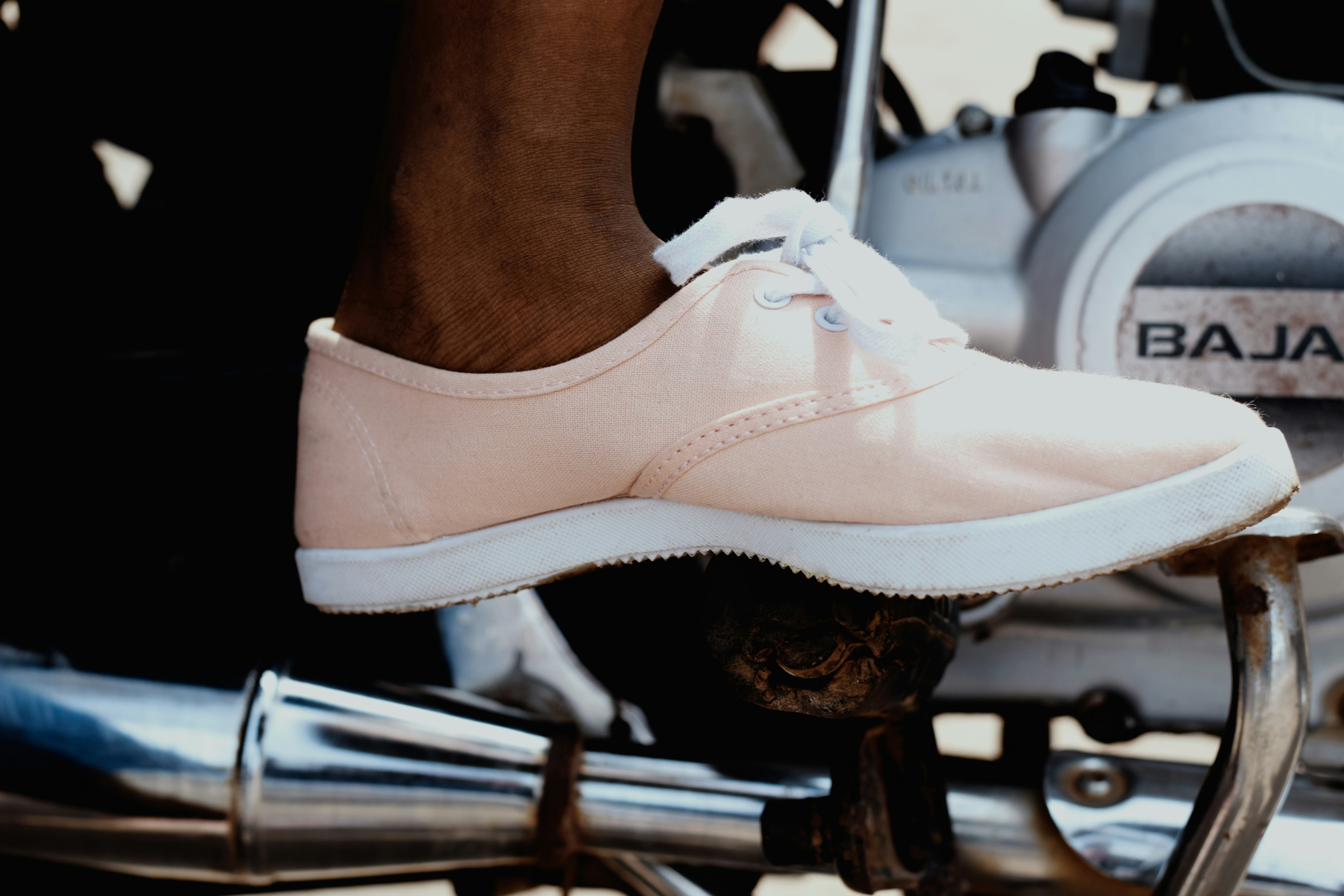 person wearing pink sneaker riding on Bajaj motorcycle