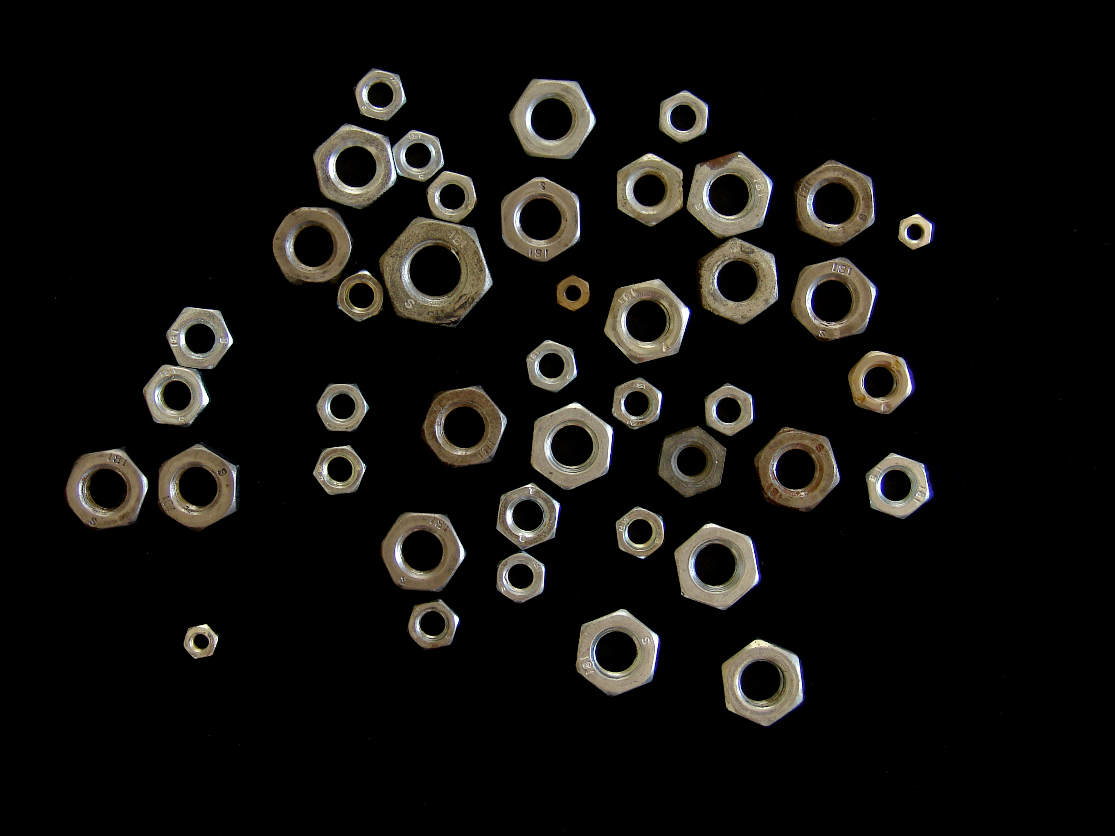 Steel hex nuts and washers on a black background
