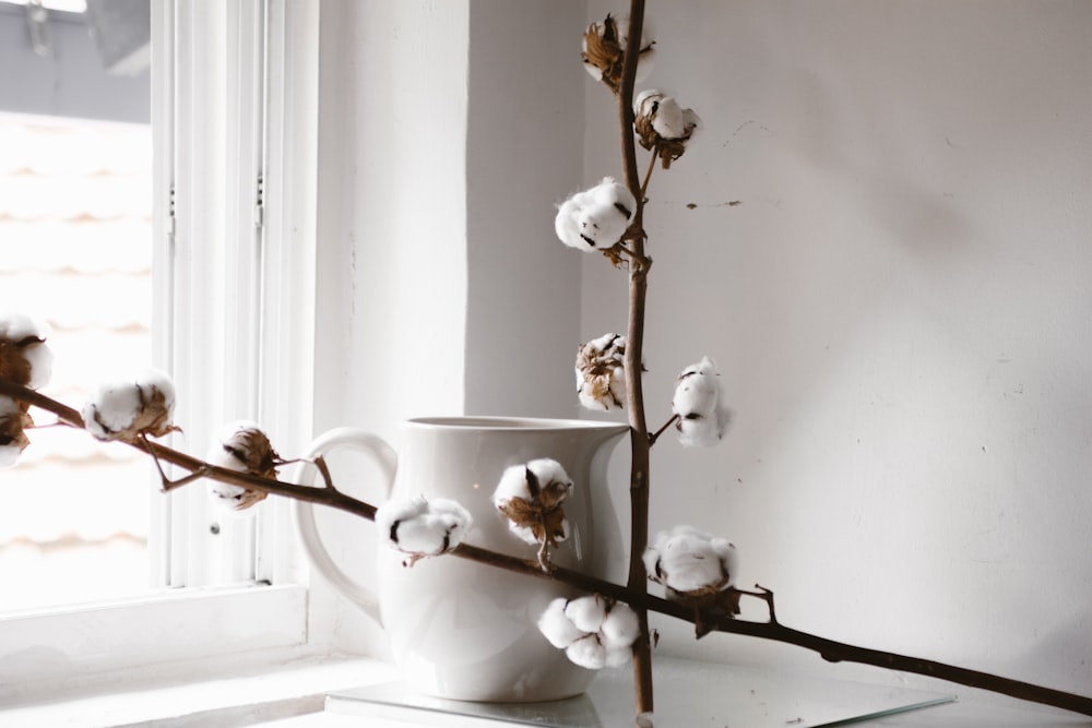 white flowering brown plant beside white ceramic teapot