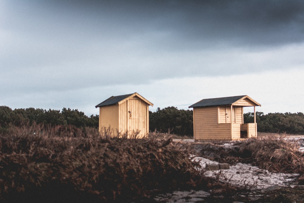 two beige wooden barn houses on field