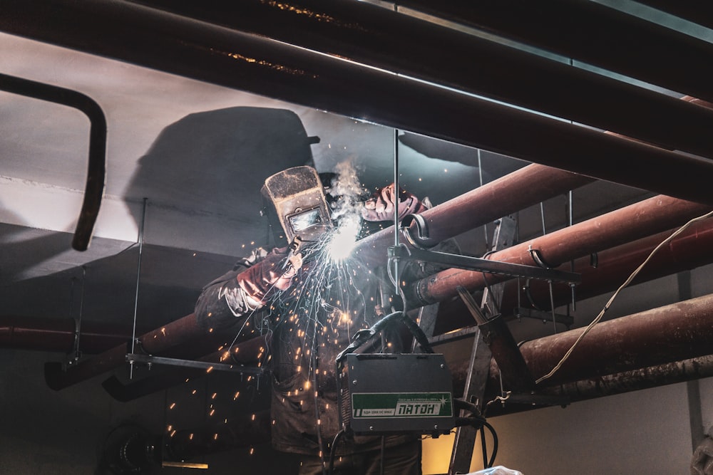 person welding brown metal pipe