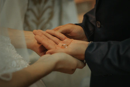 Close-up of hands gently arranging wedding details on a minimalist black background.