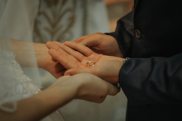 Close-up of hands holding wedding rings during a heartfelt moment.