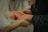 Close-up of hands holding wedding rings on a wooden table.