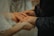 Close-up of hands holding wedding rings on a wooden table.