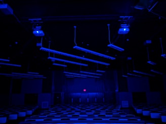 A sleek, glowing classroom filled with focused students working on futuristic tech devices under ambient blue lighting.