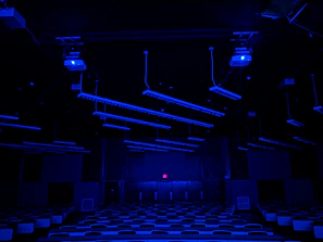 A panoramic view of the modern MBQ Academy classroom bathed in deep navy and emerald lighting.