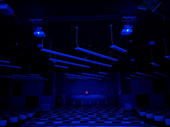 A sleek, glowing classroom filled with focused students working on futuristic tech devices under ambient blue lighting.