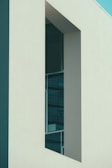 A modern architectural structure with clean lines and a minimalistic design. The building features large glass windows set within smooth, light-colored walls, contrasting with the deep shadows cast by the angular shapes.