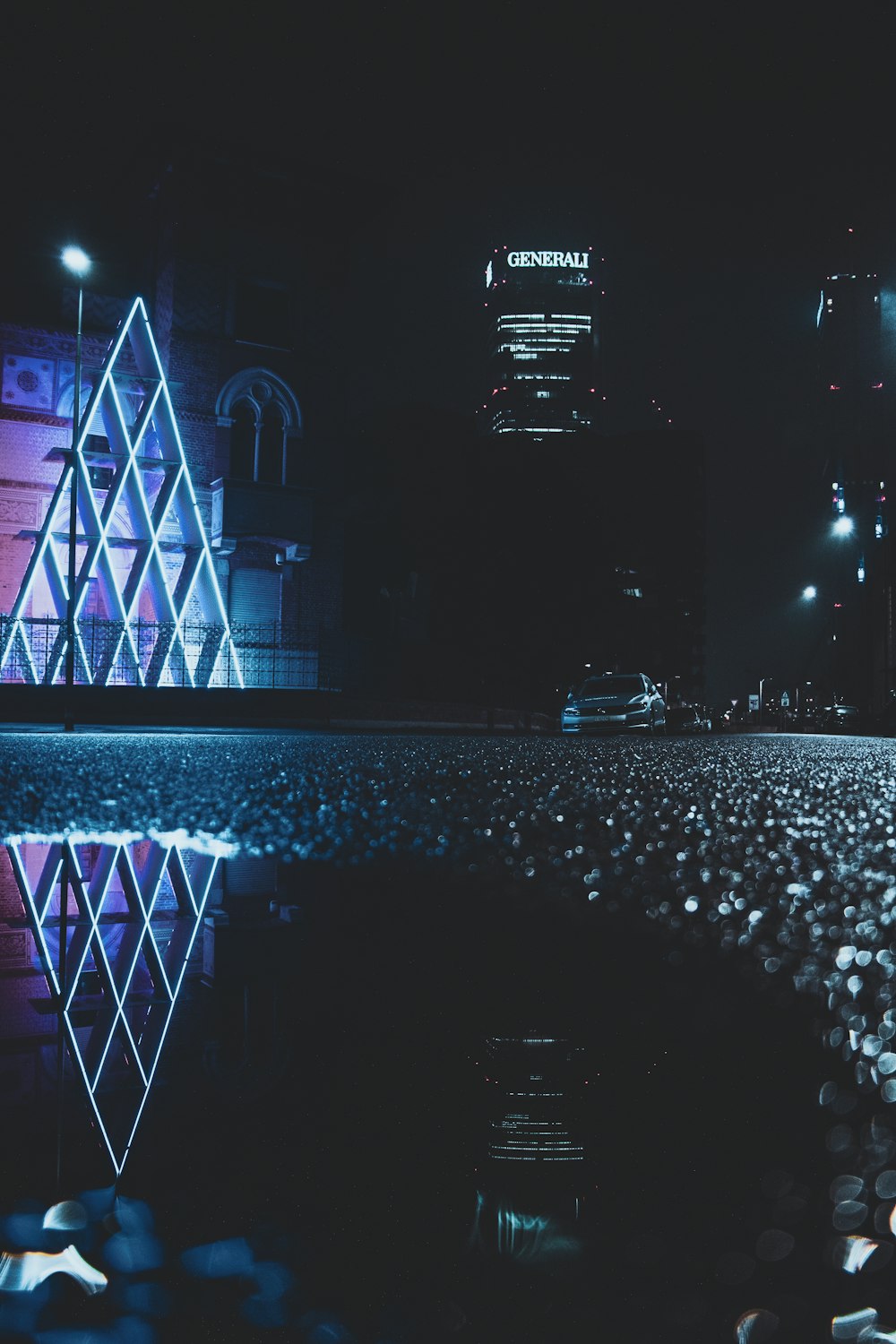 Una ciudad de noche con un reflejo de un edificio en el agua