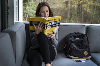woman sitting on sofa beside bag while reading