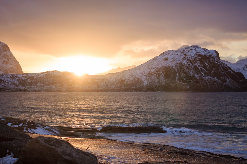 body of water near mountain during golden hour