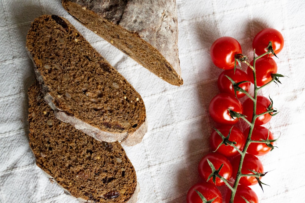 tomates cherry rojos junto a pan de molde sobre textil blanco