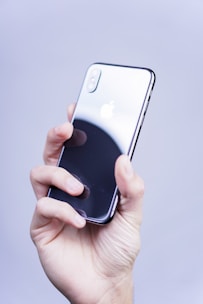 Close-up of a hand holding a sleek iPhone against a modern digital background