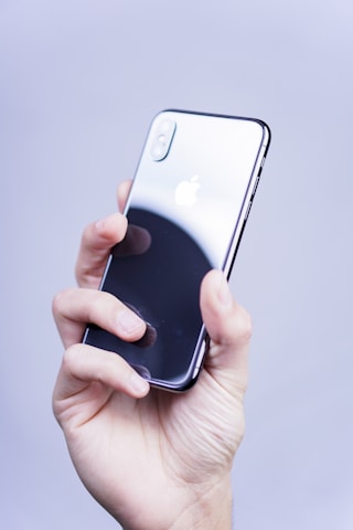 Close-up of a hand holding a shiny, gently used iPhone with a clean design.