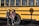 Photo of a smiling mother standing beside a school bus