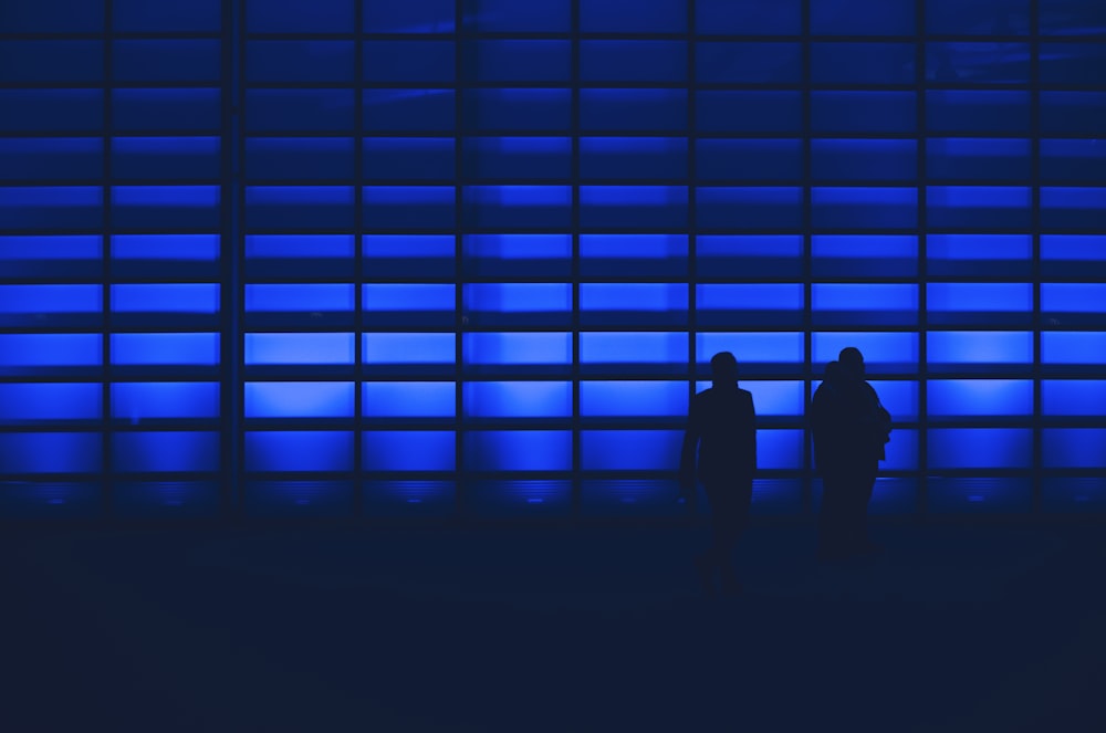 photo de silhouette de deux personnes debout près du mur