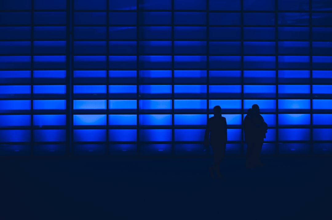 silhouette photo of two person standing near wall