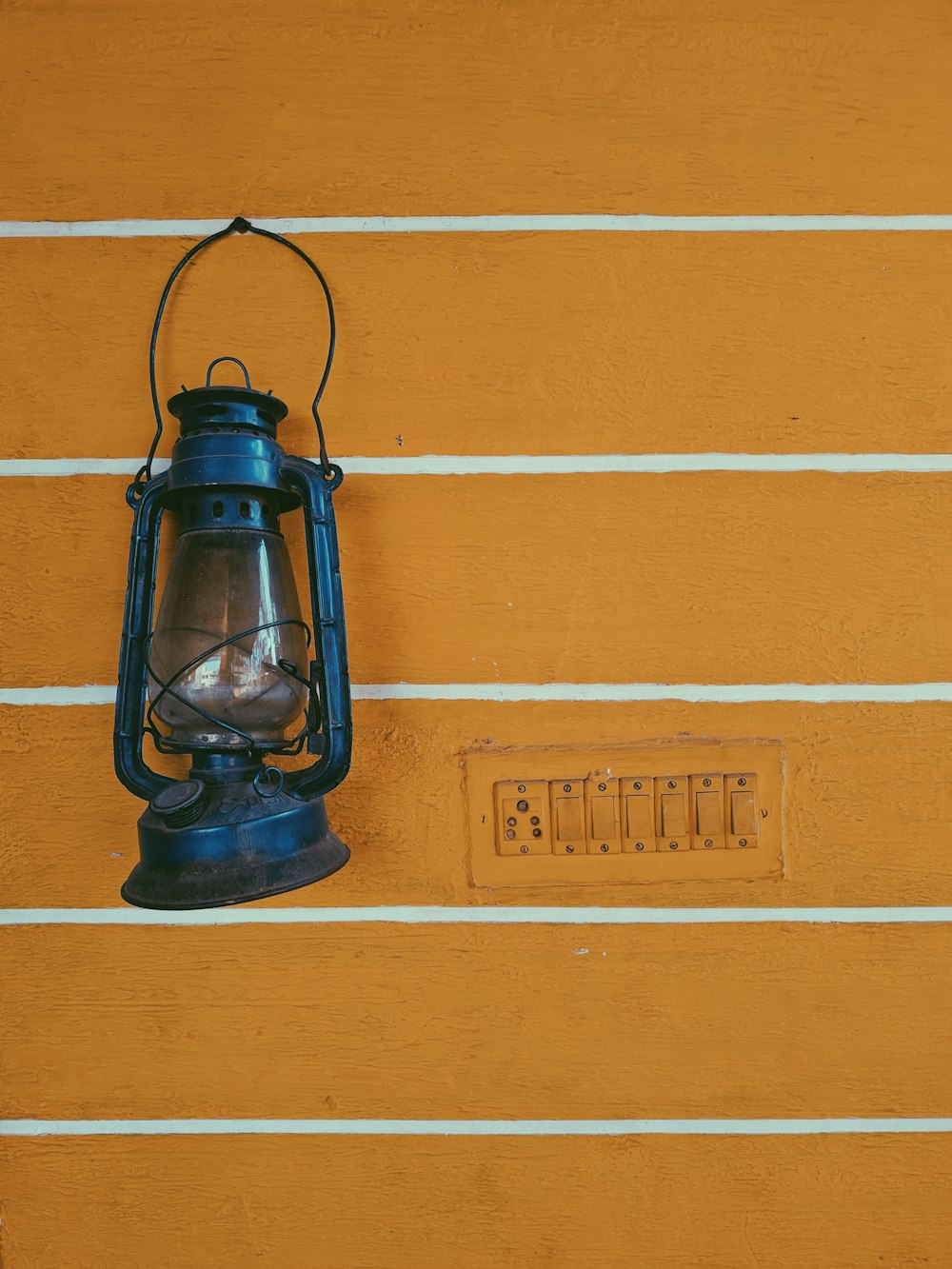 lanterna de querosene azul na parede listrada amarela e branca