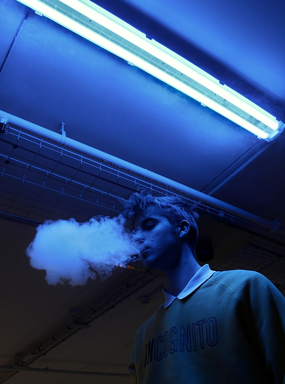 boy in grey shirt blowing smoke