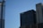 A skyline with modern office buildings under a clear blue sky. One building has reflective glass panels, and another features a sign that reads 'visit California'. The structures are primarily vertical with different textures and designs.