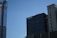 A skyline with modern office buildings under a clear blue sky. One building has reflective glass panels, and another features a sign that reads 'visit California'. The structures are primarily vertical with different textures and designs.
