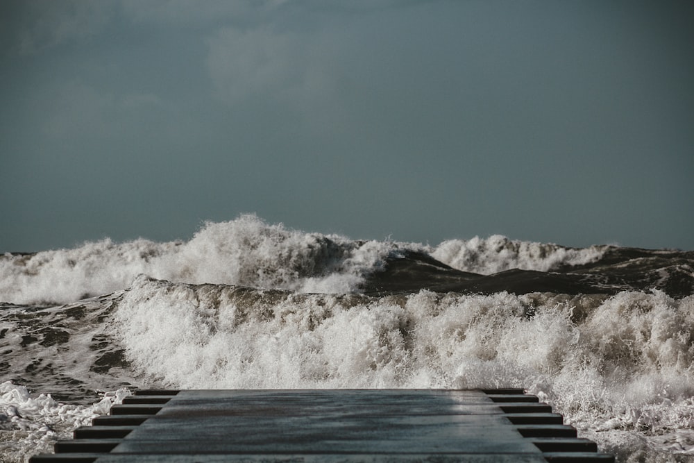 gray wooden dock and beach big waves