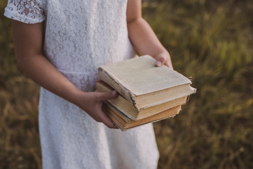 girl in white dress holding books