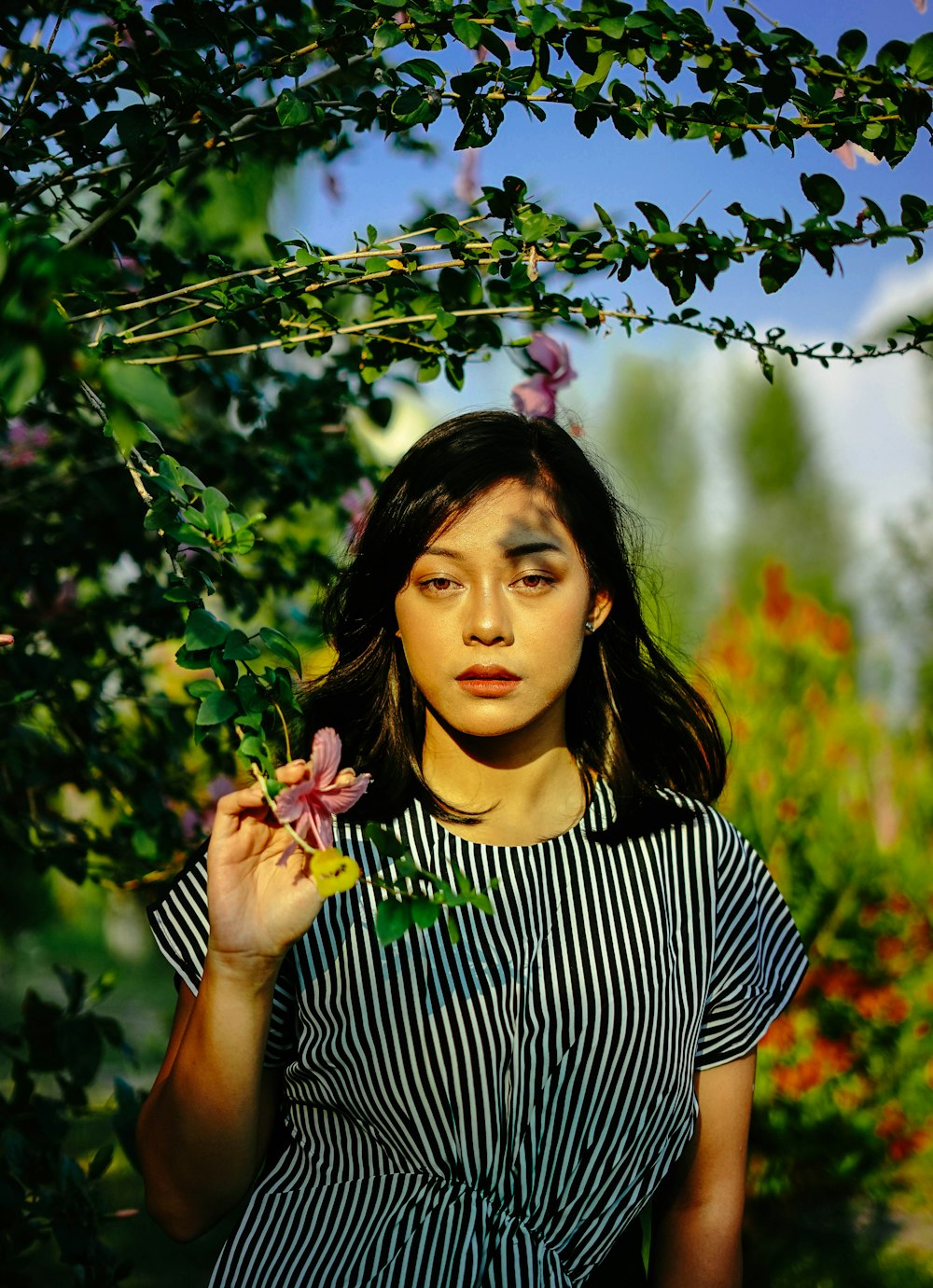 a woman holding a flower in front of her face