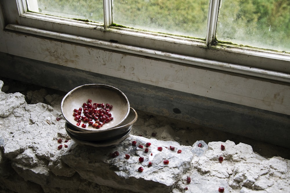 round red fruits on brown bowl near window
