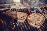 Close-up of juicy steak sizzling over glowing charcoal embers.