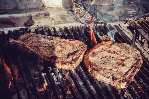 Close-up of a perfectly cooked, juicy marbled Angus steak sizzling on a grill.