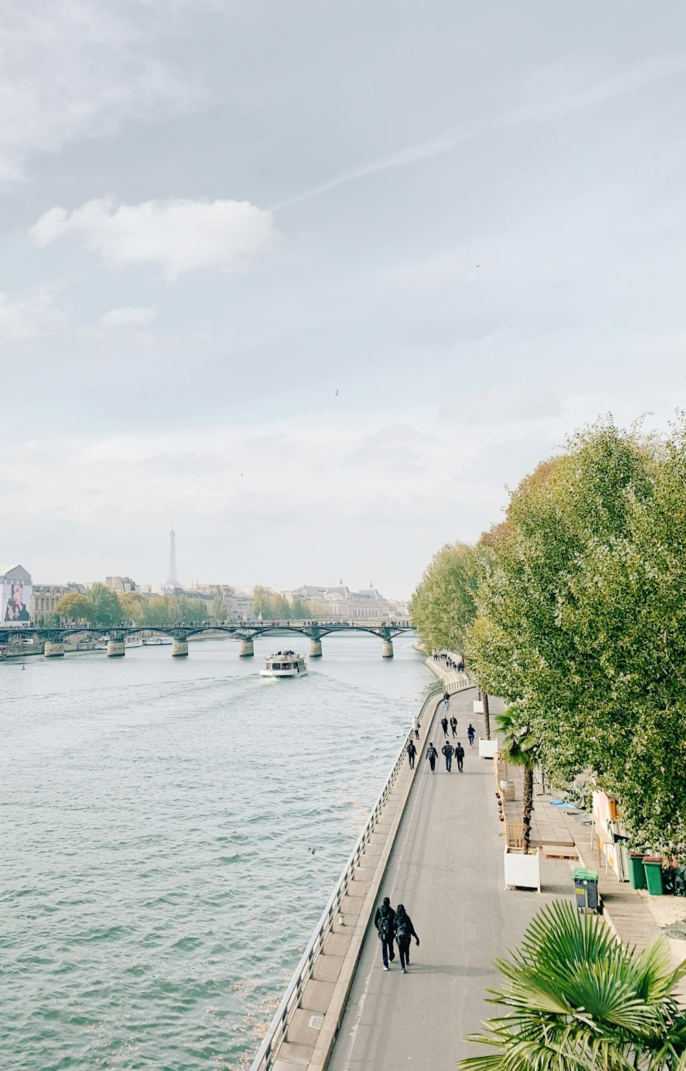 aerial photography of people walking on concrete road near body of water during daytime