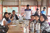 Travelers sharing a meal and stories at a rustic resort dining area, smiles all around.