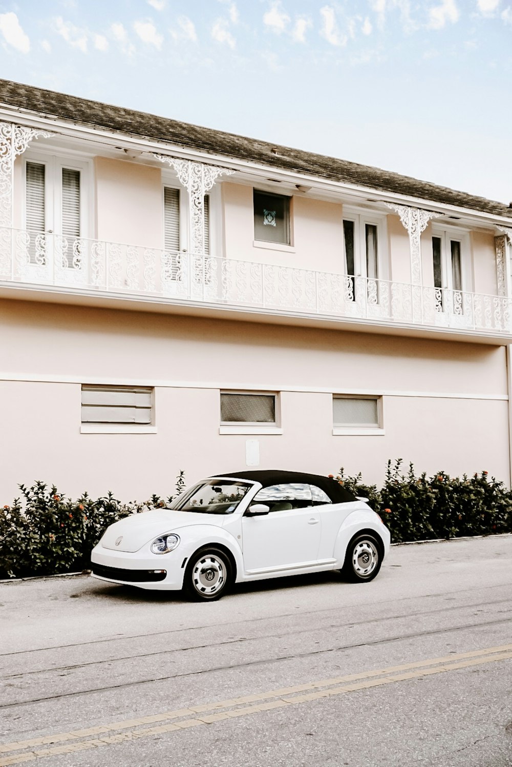 white Volkswagen New Beetle convertible parked near concrete building during daytime