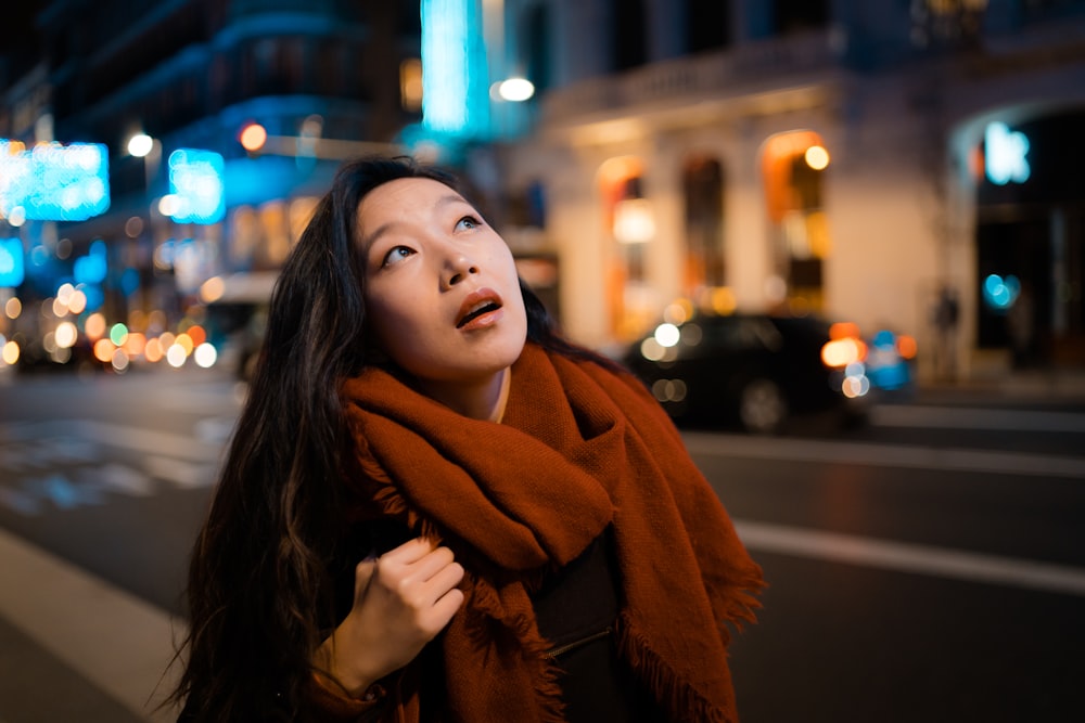 standing woman look stunned wearing brown fringe scarf during night time