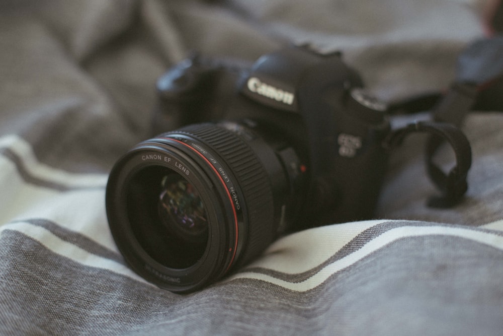 black Canon DSLR camera on white and grey textile