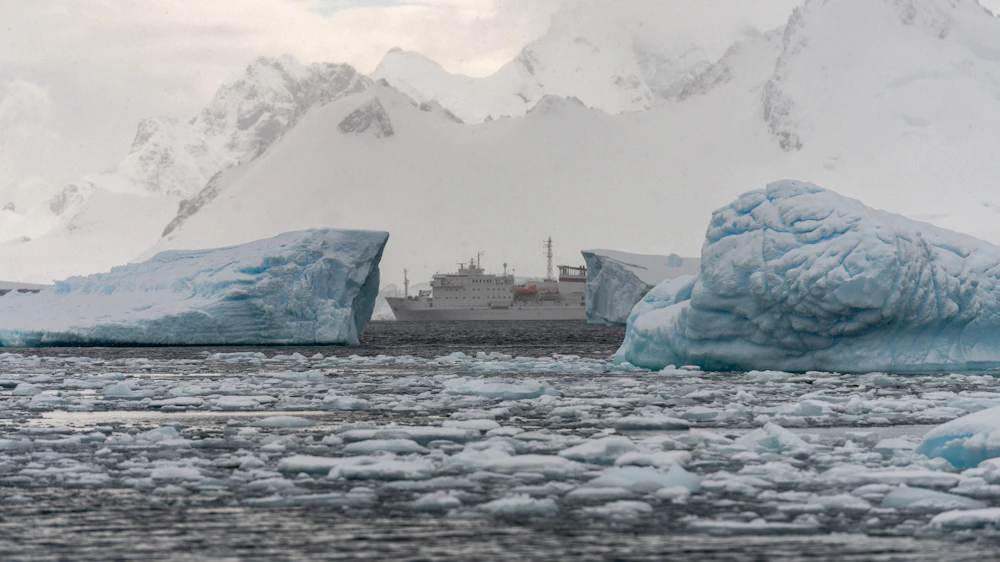 Expedition cruise ship sailing alongside icebergs in Antarctica