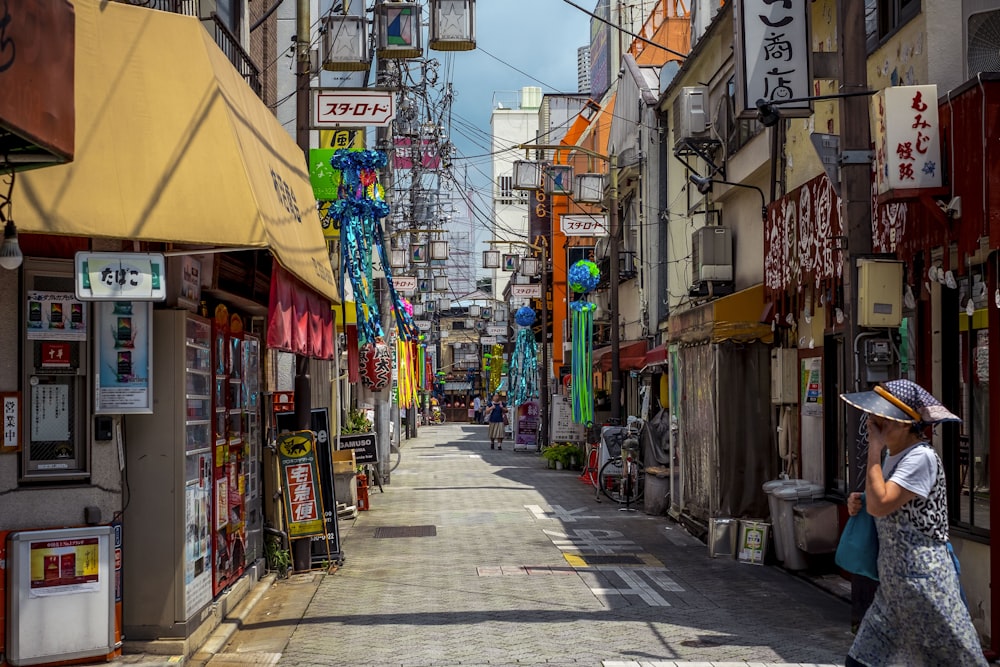 woman crossing the alley between stores during daytime